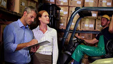 Warehouse management talking with forklift driver behind