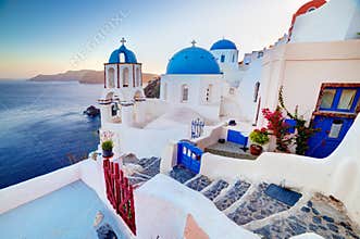 Oia town on Santorini island, Greece at sunset. Rocks on Aegean sea.