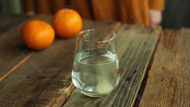 Hands add an effervescent tablet of vitamin C to a glass of water