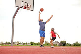 The girl throws a basketball into the ring with all her might, bypassing father in game