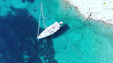 Aerial Top View of Luxury Yacht Anchored in Turquoise Clear Water Near Rocky Coast