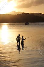 Father and son family fishing at sunset