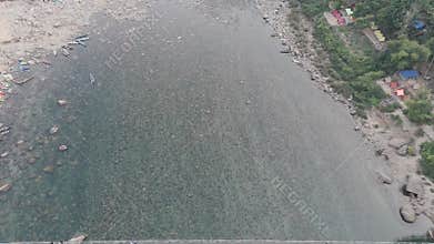 Top-down aerial view of the crystal-clear water of the Umngot River in Shnongpdeng, Meghalaya, revealing the pebble riverbed