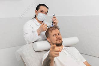 Trichologist doing man improve hair growth procedure, dermapen microneedling, vitamin injections