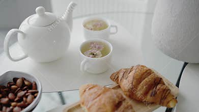 Elegant Breakfast Scene with Tea, Croissants, and Almonds on White Table
