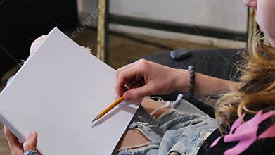 Woman draws with yellow pencil on small canvas resting on legs