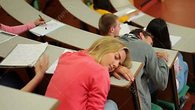 Student asleep at desk in lecture hall