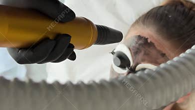 Young woman getting carbon laser facial at beauty clinic. Professional skincare