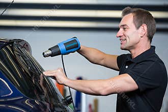 Car wrapper using heat gun and squegee for tinting window