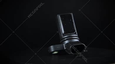 Electromagnetic crankshaft position sensor of car engine rotates on black background. Spare parts catalog.