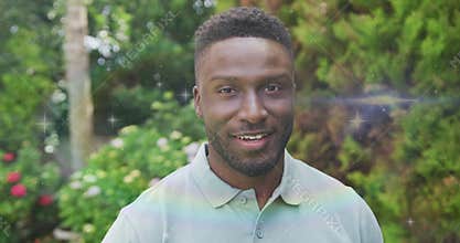 Mid adult man wearing polo turning head activating rainbow shimmer in garden for business branding