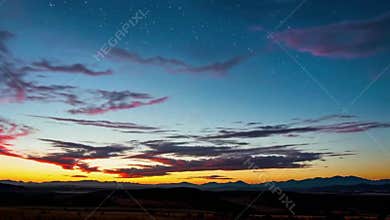 Sunrise over the mountains with dramatic clouds and starry sky.