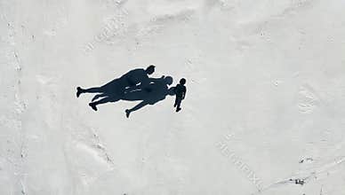 Aerial view captures shadows of a family walking on white sand creating a minimalist and abstract beach scene on a sunny day