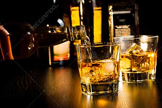 Barman pouring whiskey in front of bottles, focus on top of bottle