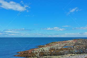 A huge pink rock formation in the Saint Lawrence River, with the vastness of the water and sky. Quebec, Canada