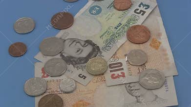 Sterling UK cash and coins rotating a blue background.