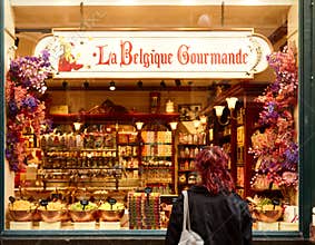 Woman with red hair admires colorful sweets in shop window of La Belgique Gourmande in Brussels