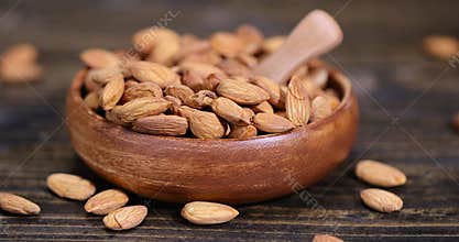 yellow brown whole nuts of unroasted almonds with a wooden spoon