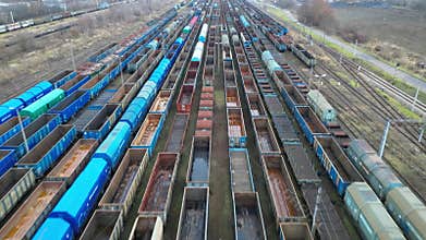 Aerial view of a vast freight train yard showcasing rows of colorful train cars, with a gradual zoom out revealing the expansive