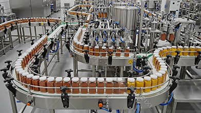Automated Beverage Production Line with Numerous Small Brown and Yellow Bottles Moving in a Factory Facility under Bright