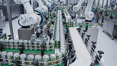 Automated beverage production line with robotic arms processing shiny aluminum cans on a conveyor belt under bright factory