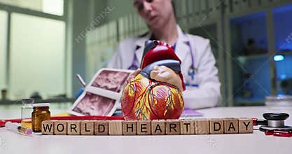 Text World Heart Day on wooden cubes in woman cardiologist office