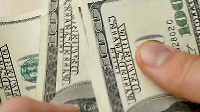 Fingers counting hundred dollar bills