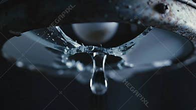 Close Up Macro Shot of Water Dripping from Old Rusty Fixture with Dramatic Lighting