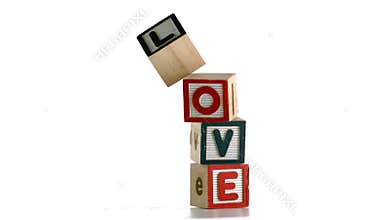 Stacked building blocks spelling out love falling over