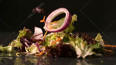 Salad falling onto black surface