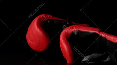 Red boxing gloves falling on black background