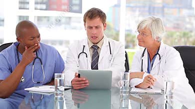 Serious doctor talking with his colleagues about a tablet pc