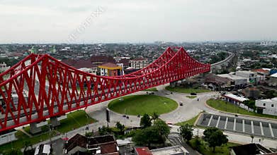 An aerial view of Simpang Joglo, Solo, featuring a striking red steel bridge above busy roads, buses, and cars