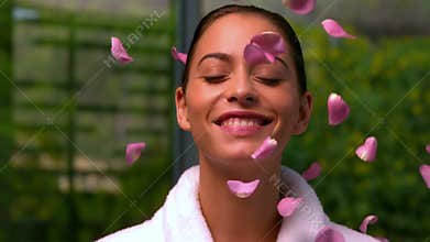 Beautiful brunette in bathrobe at the spa throwing up rose petals