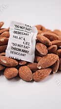 Almonds and silica gel pack on a white background