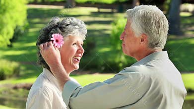 Smiling mature man giving a flower to his wife