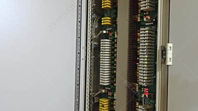 Closeup electrical control panel interior showing organized wiring, rows of terminal blocks, yellow busbar modules