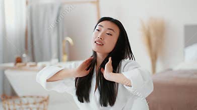 Indoors portrait of young well groomed asian woman preening at bathroom, fixing her hairstyle and smiling