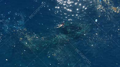 People swimming in dirty ocean with floating plastic pollution. Above view