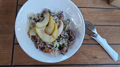 Seafood salad, squid with tender lettuce leaves and pieces of baked pear in a cozy summer cafe