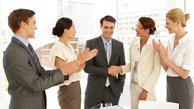 Business people shaking hands at interview while others clap