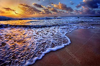 Serene beach destination sunrise with breaking wave crest and sea foam