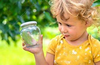 A child studies a beetle in a jar with a magnifying glass. Selective focus.
