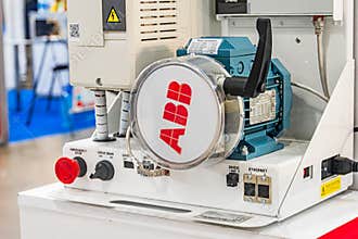 Modern industrial exhibition setting with ABB machine in blue and white, featuring control buttons and dials, centrally positioned