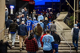 Blue Jays fans walking toward Rogers Centre before the baseball game at night.