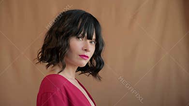 Beautiful fashionable brunette woman with trendy bob haircut, wavy dark hair with bangs, wearing bright make-up and red lipstick