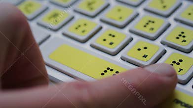 Hands typing on a Braille keyboard. Close-up, fingers moving across tactile keys