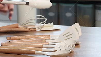 A woman is reviewing a set of kitchen utensils. She is laying them out on the table