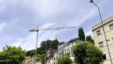 Tower crane above hillside residential buildings in Porto, Portugal, facades