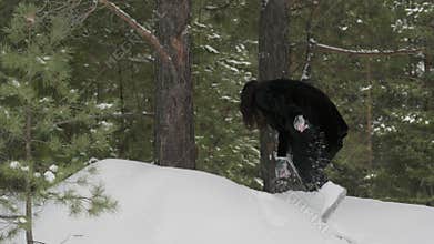 Woman crouching down on snowy ground in winter forest exploring nature